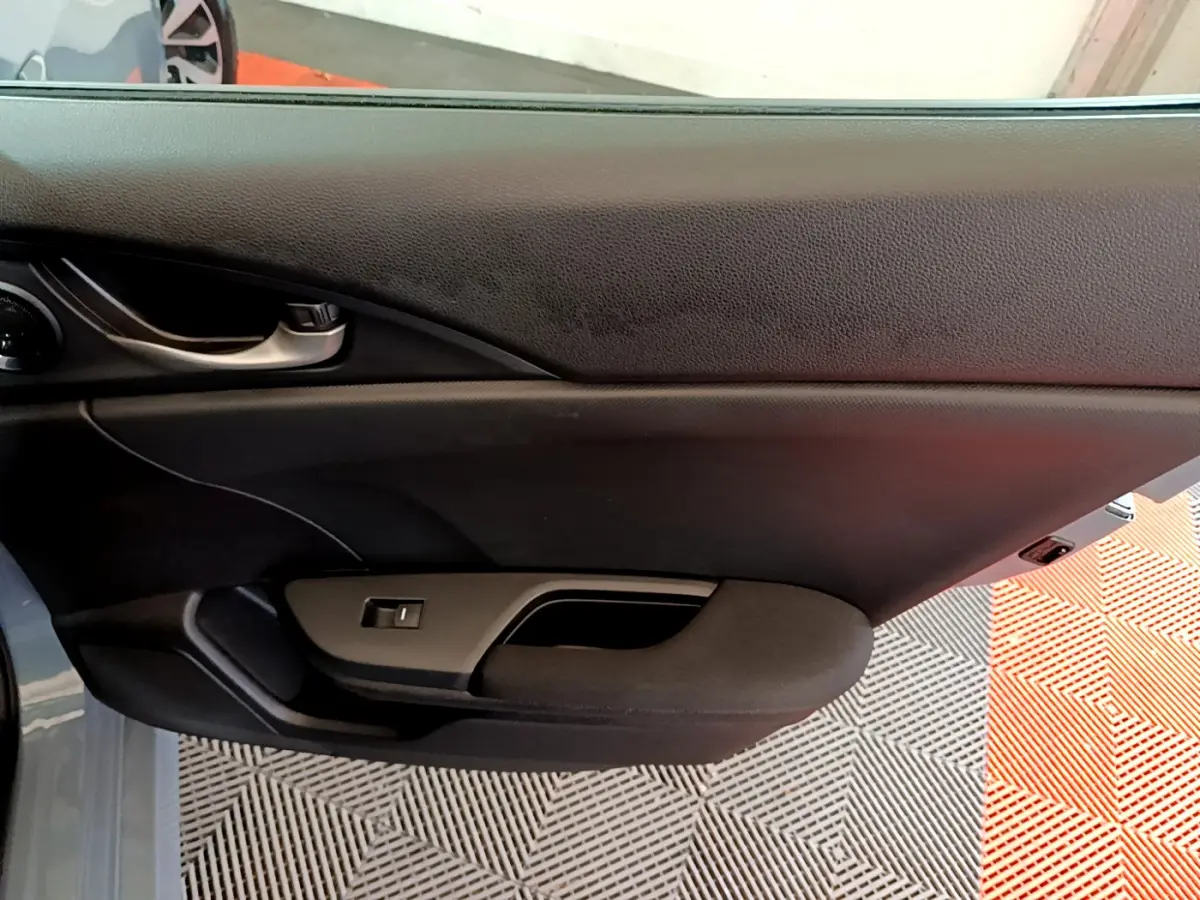 Intérieur montrant la porte côté gauche de la Honda Civic 1.0 i-VTEC Exclusive 2020 en gris foncé, avec poignée et commande vitre.