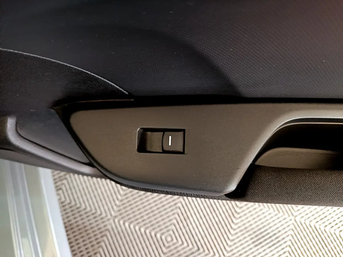 Détail du bouton d'ouverture du toit ouvrant électrique sur la garniture intérieure noire d'une Honda Civic gris foncé.