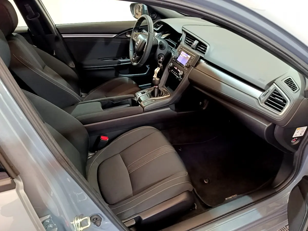 Intérieur avant droit de la Honda Civic 1.0 i-VTEC gris foncé, avec tableau de bord moderne et boîte manuelle.