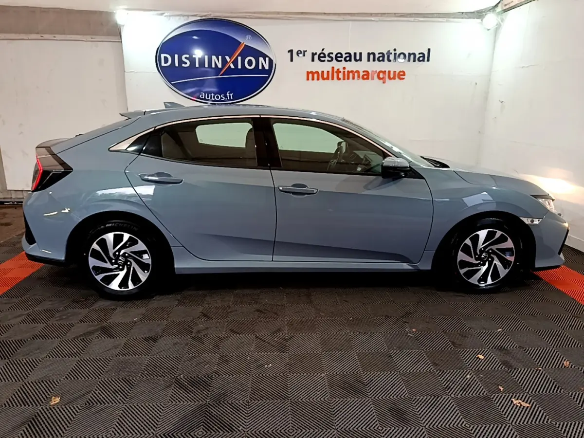 Profil côté gauche d'une Honda Civic 1.0 i-VTEC Exclusive gris foncé, avec jantes alliage et feux arrière distinctifs.