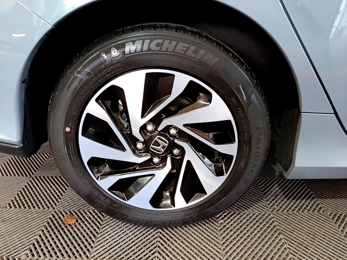 Gros plan sur la jante avant droite de la Honda Civic gris foncé, avec pneu Michelin et logo Honda central.