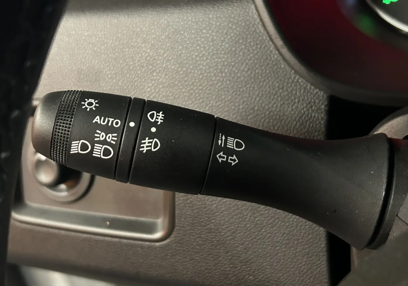 Gros plan sur la commande des phares et clignotants dans l’habitacle du Dacia Duster blanc 2024.