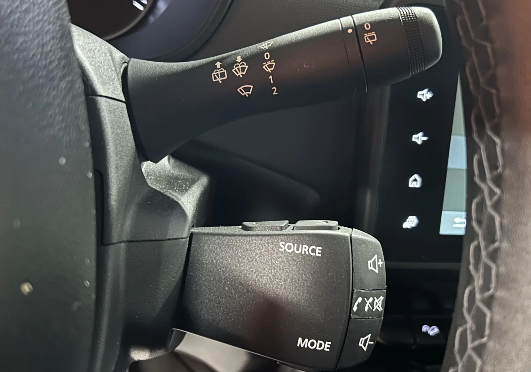 Gros plan sur les commandes au volant du Dacia Duster 2024, côté gauche, avec boutons source et mode visibles.