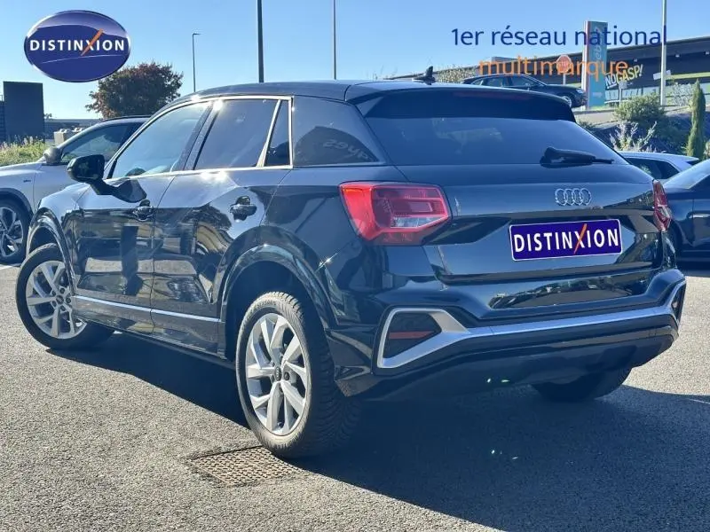 Vue 3/4 arrière droite d'un Audi Q2 noir brillant avec jantes alu et vitres arrière surteintées.