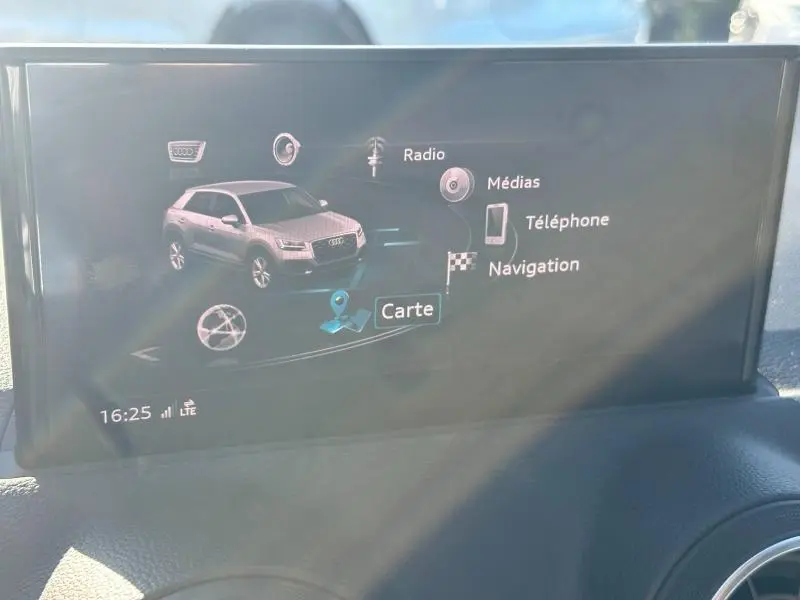 Écran multimédia intérieur affichant un Audi Q2 blanc en vue 3/4 avant avec menu de navigation et médias.