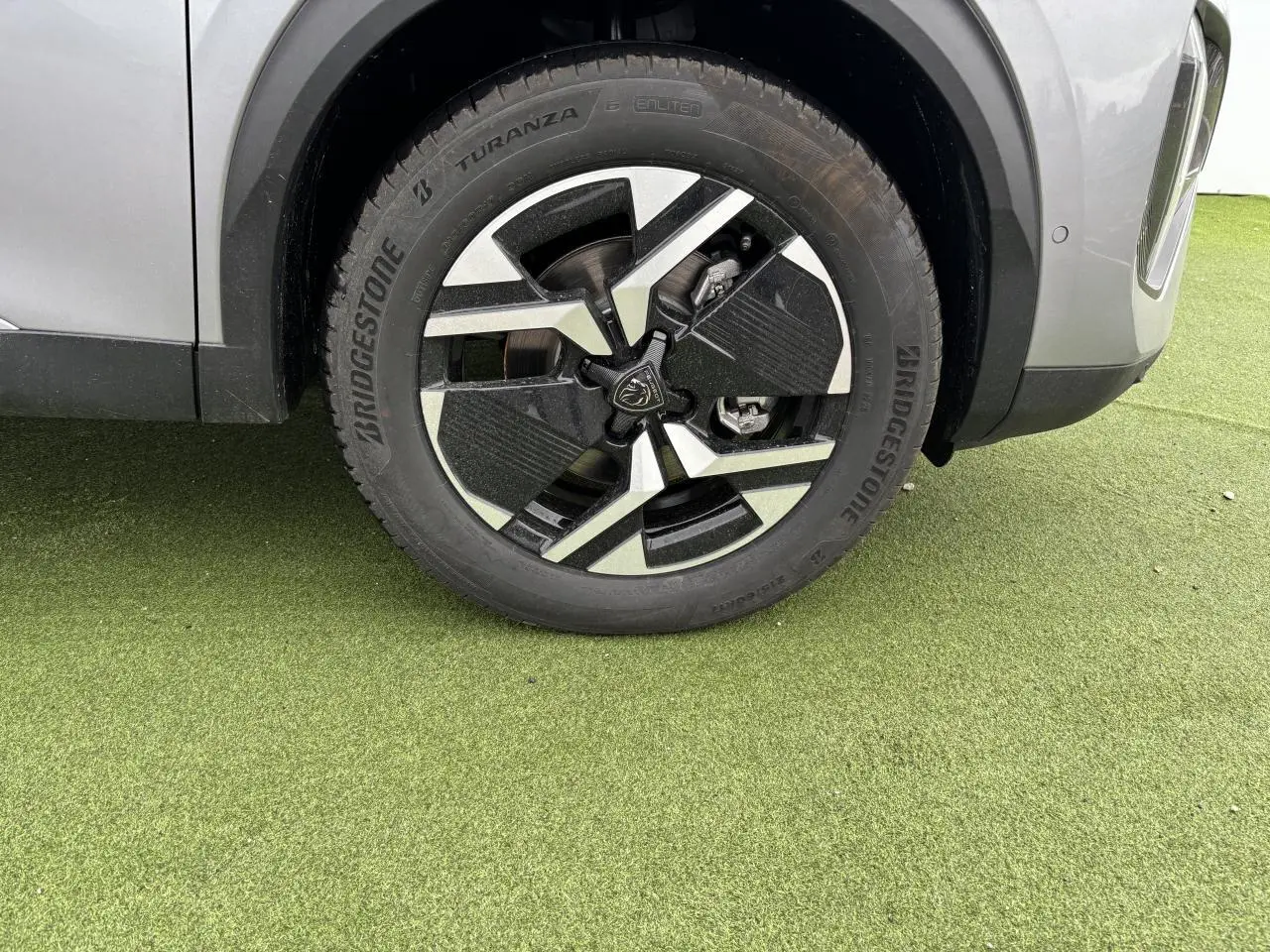 Gros plan sur la roue avant droite du Peugeot 2008 gris Artense avec jante alliage bi-ton noir et argent.