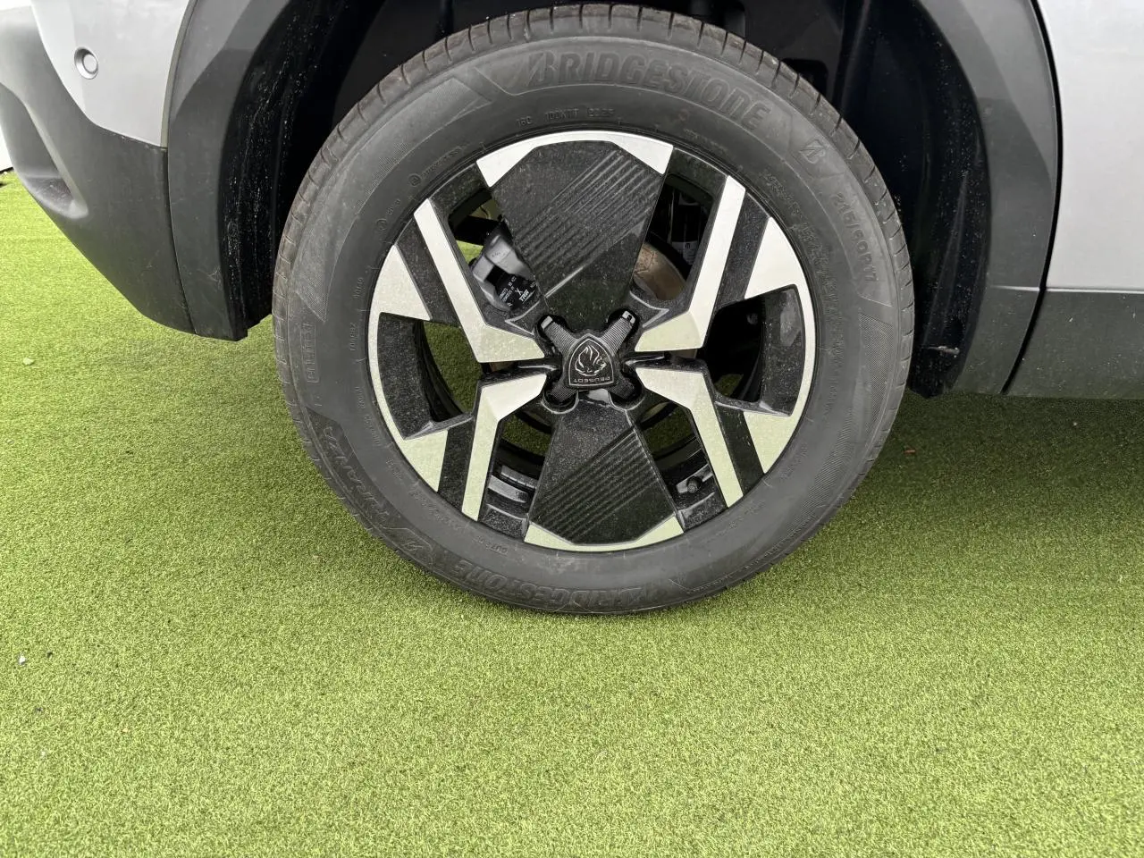Gros plan sur la jante alliage 17'' bi-ton noir et argent du côté avant gauche du Peugeot 2008 gris Artense.