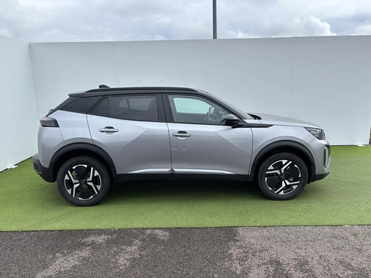 Peugeot 2008 gris Artense toit noir en vue profil côté gauche sur fond neutre, jantes alliage bi-ton visibles.