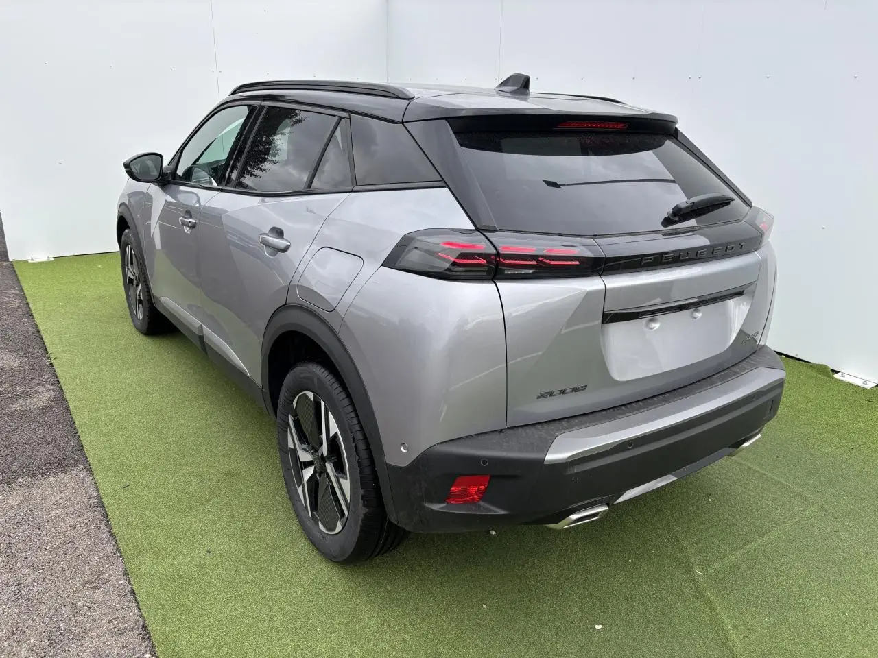 Vue 3/4 arrière droite du Peugeot 2008 gris Artense avec toit noir et feux arrière LED 3 griffes, jantes bi-ton 17 pouces.