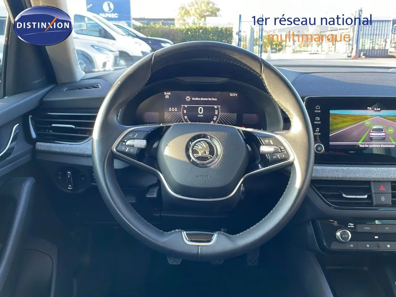 Vue intérieure centrée sur le volant noir du Skoda Kamiq 2024 avec tableau de bord digital et écran tactile.