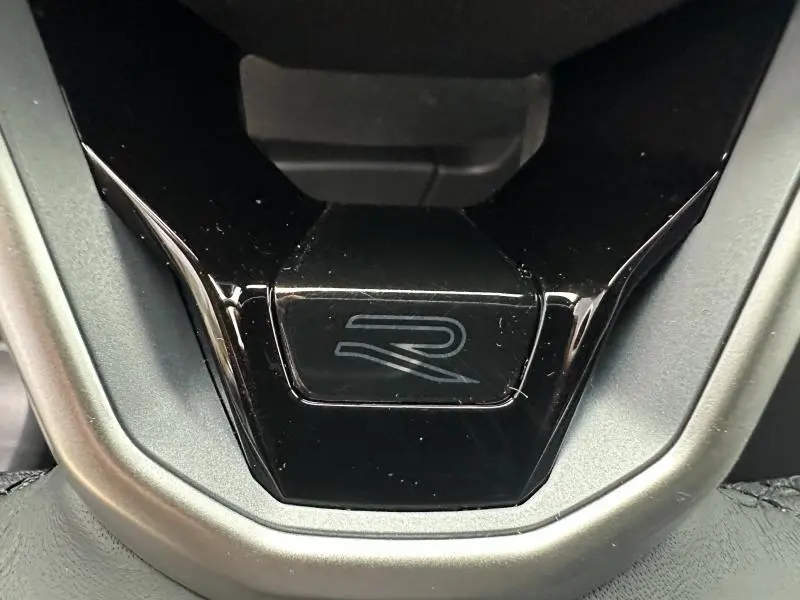 Gros plan sur le bouton R-Line noir brillant du Volkswagen T-Roc gris 2025, version 1.5 TSI Evo2 150ch DSG7.