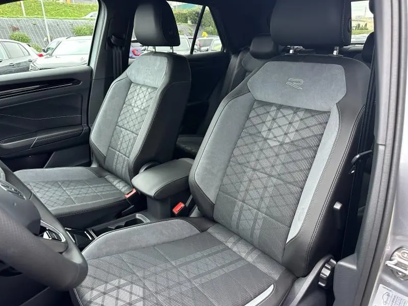 Intérieur du Volkswagen T-Roc 2025, sièges avant gris avec surpiqûres et logo R-Line visibles côté conducteur.