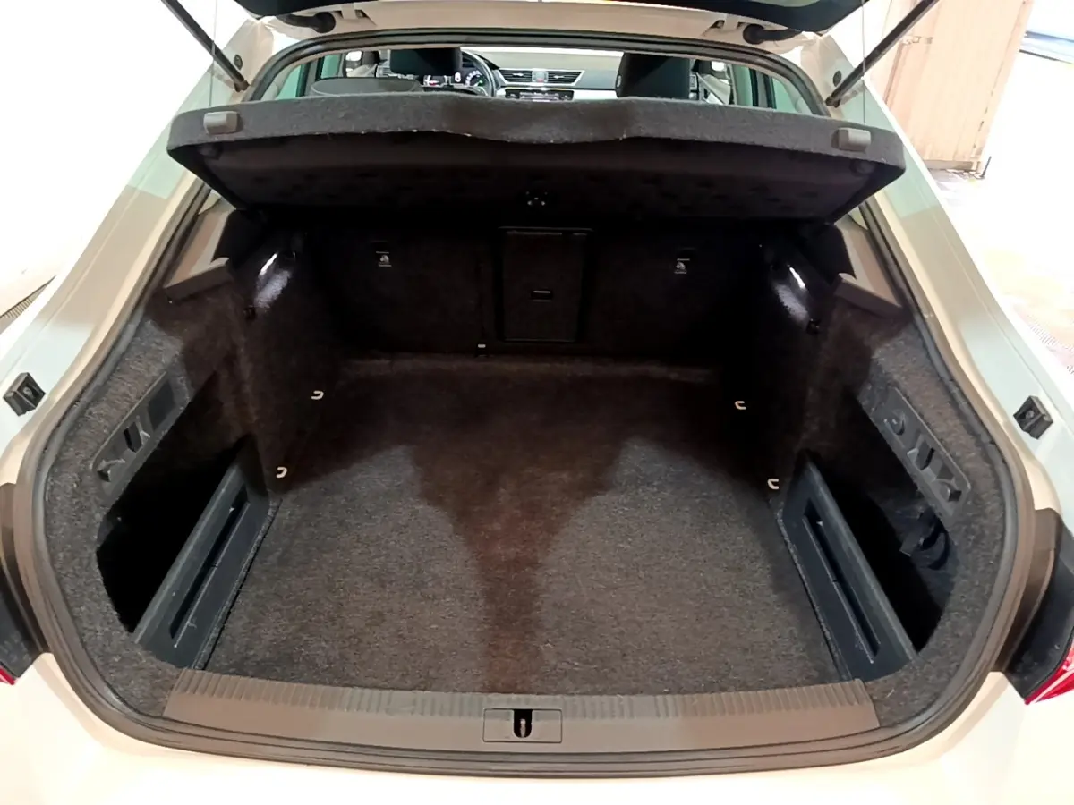 Vue intérieure du coffre ouvert d'une Skoda Superb blanche 2021, montrant un espace de rangement propre et spacieux.