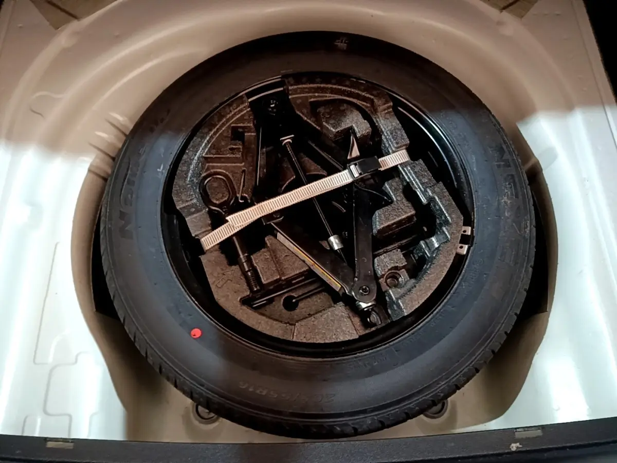 Gros plan sur la roue de secours en jante acier noire dans le coffre blanc d'une Skoda Superb 2021.