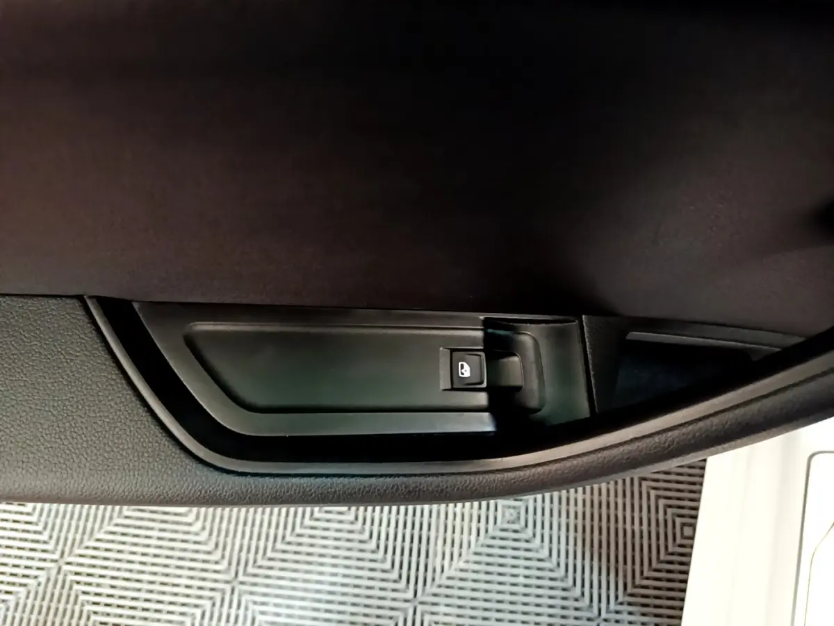 Détail de la poignée intérieure de porte côté conducteur d’une Skoda Superb blanche, bouton de verrouillage visible.