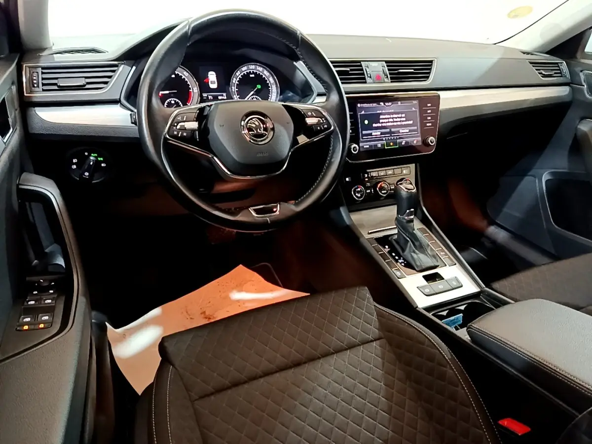 Vue intérieure côté conducteur de la Skoda Superb 2021, tableau de bord noir avec écran tactile et volant cuir multifonctions.