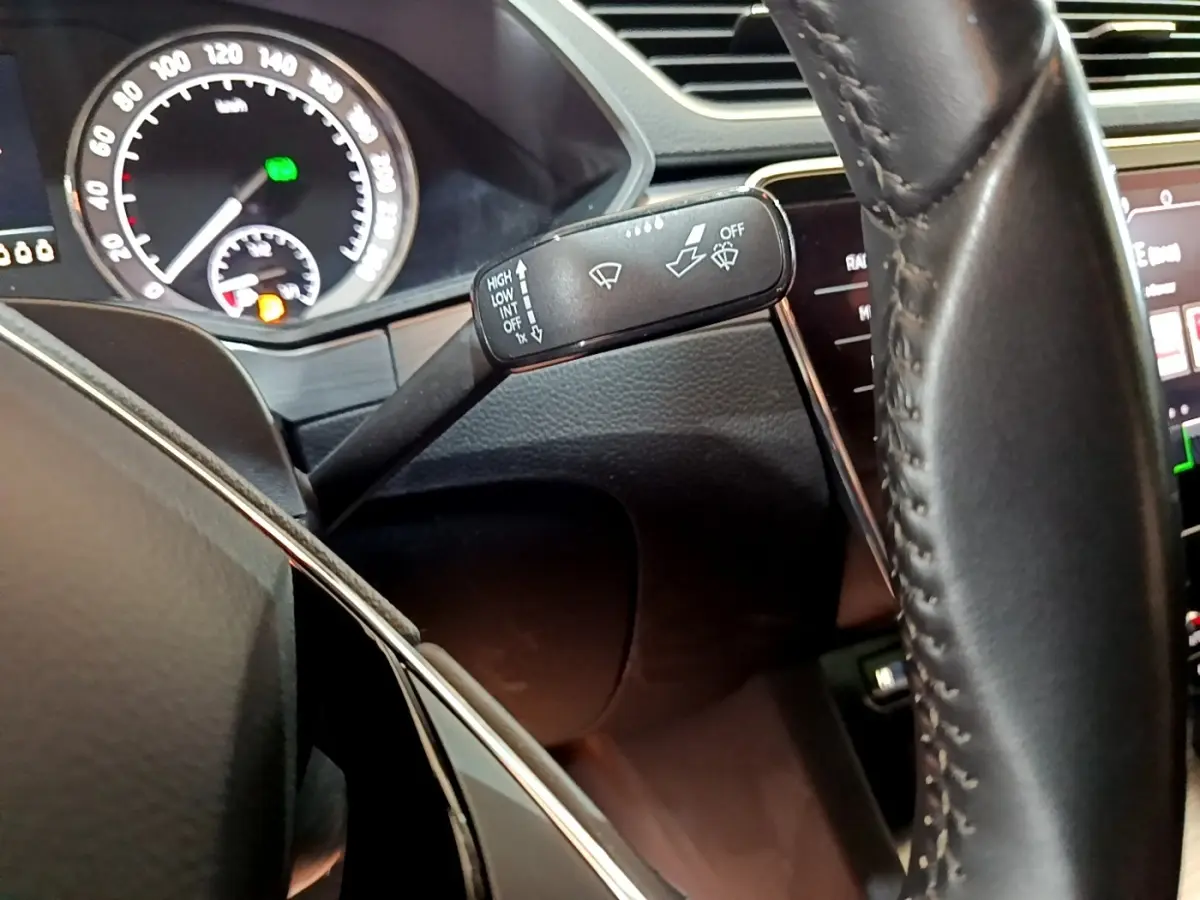 Gros plan sur le commodo d’essuie-glace et le volant cuir de la Skoda Superb 2.0 TDI 2021, tableau de bord partiellement visible.