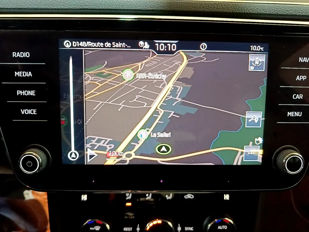 Écran tactile central du tableau de bord de la Skoda Superb blanc, affichant la navigation GPS en couleur.