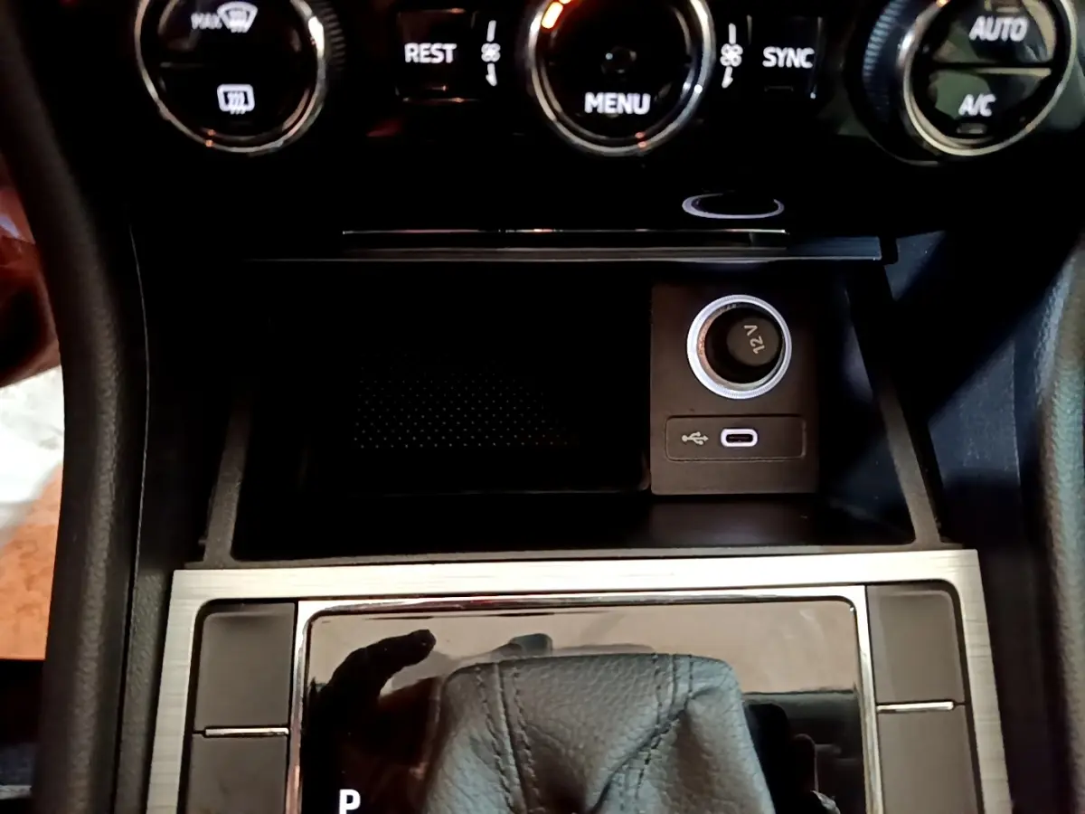 Gros plan sur la console centrale de la Skoda Superb blanche, montrant la prise 12V, port USB et commandes climatisation.