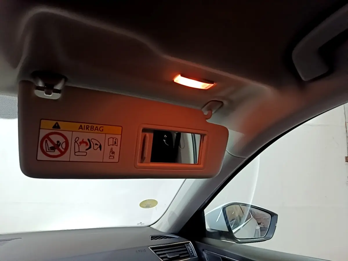 Détail intérieur du pare-soleil côté conducteur avec miroir et lumière allumée dans une Skoda Superb blanche.