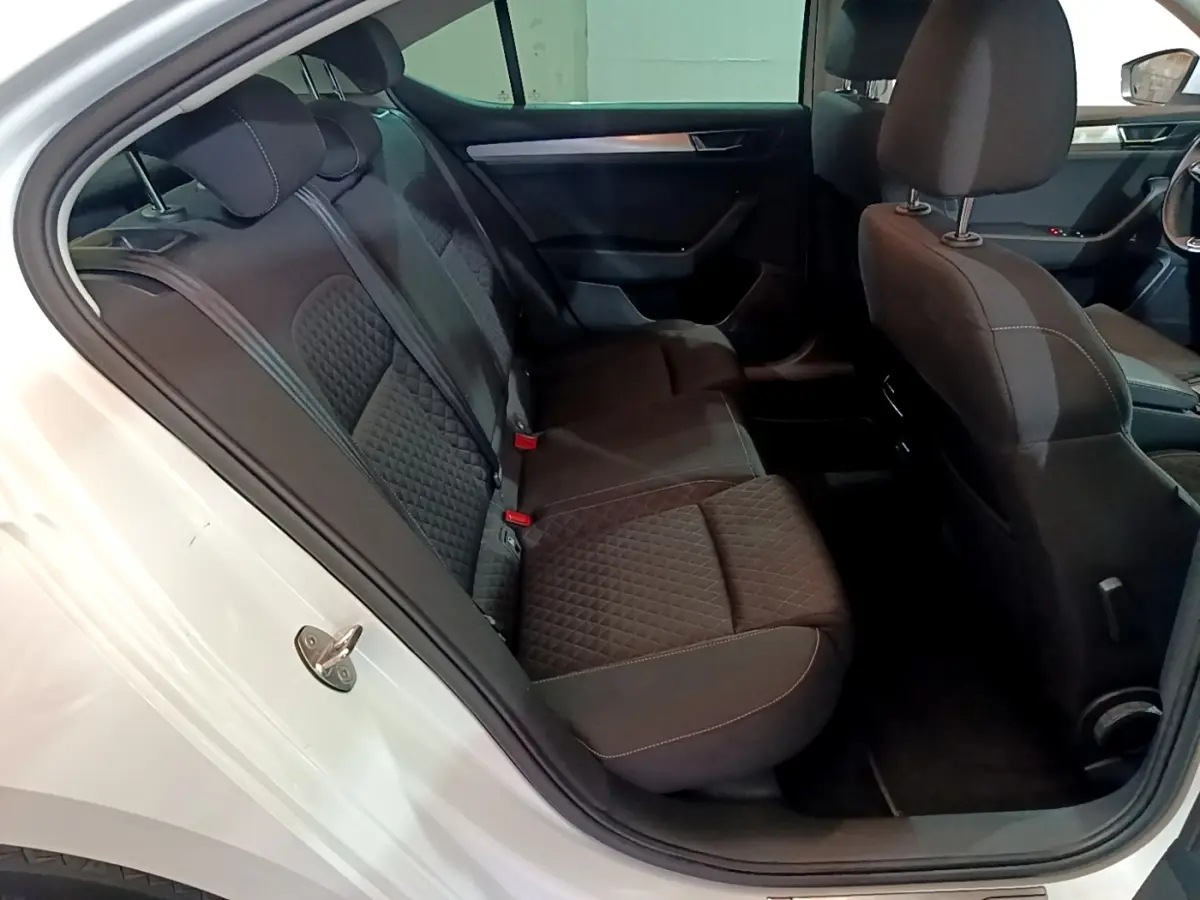 Vue intérieure côté gauche montrant la banquette arrière noire matelassée d'une Skoda Superb blanche 2021.