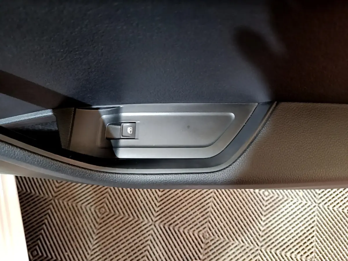 Gros plan sur le bouton de verrouillage de porte noir dans l'habitacle d'une Skoda Superb blanche, côté intérieur.