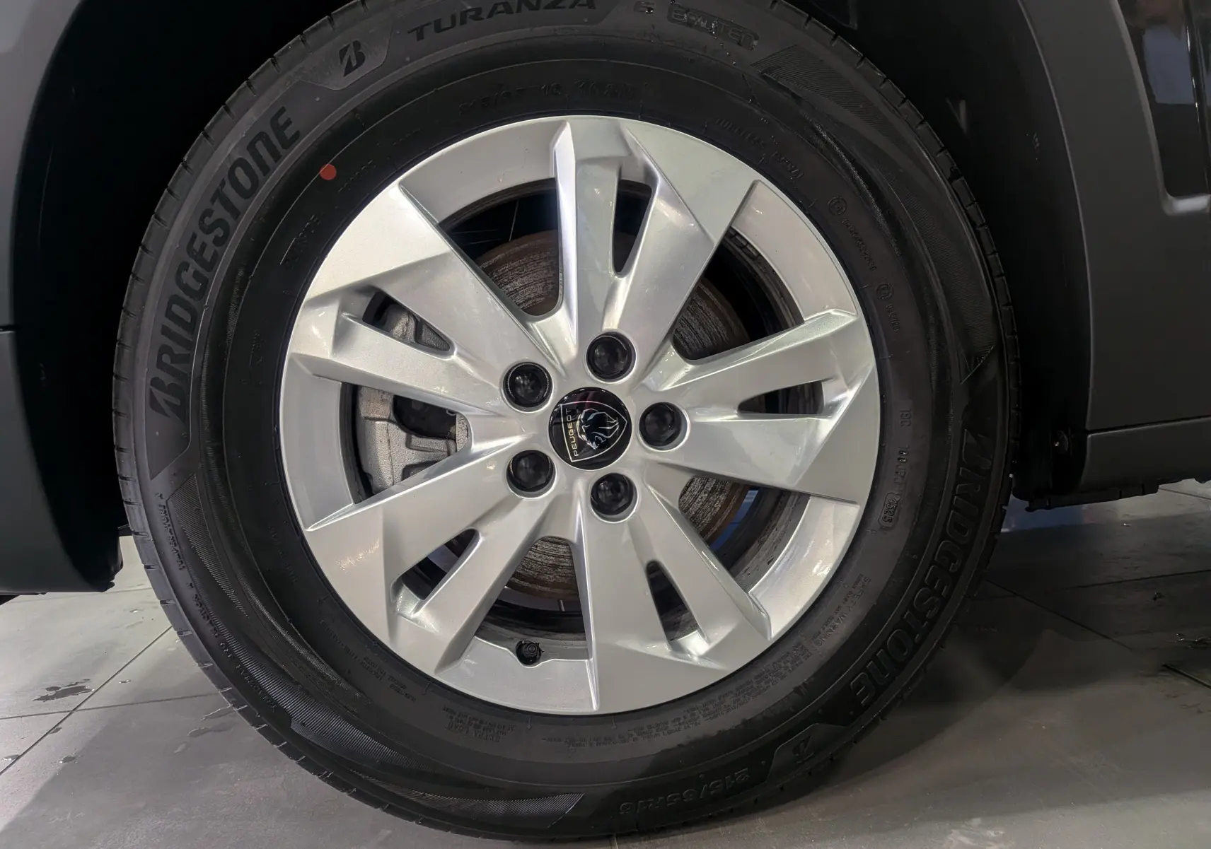 Gros plan sur la roue avant droite du Peugeot Rifter noir 2025, avec jante alliage argent et pneu Bridgestone Turanza.
