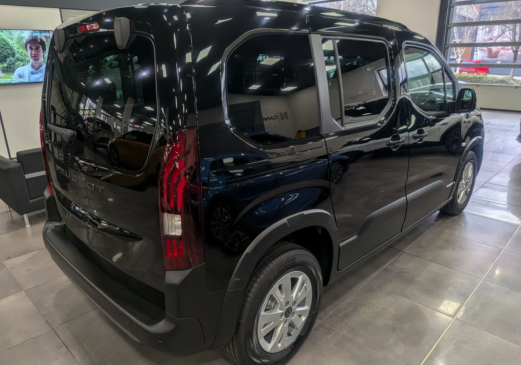 Vue 3/4 arrière droite du Peugeot Rifter noir 2025 en finition Allure, avec feux arrière verticaux et jantes alliage.