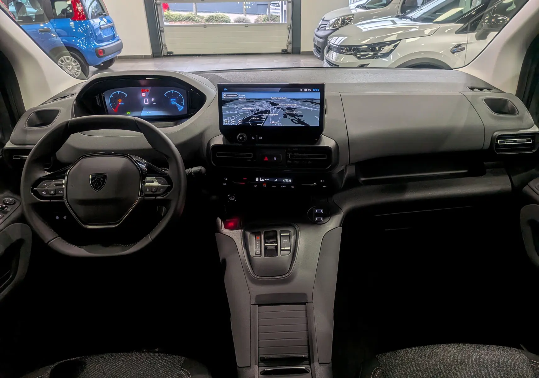 Vue intérieure avant du Peugeot Rifter 2025 noir, avec tableau de bord numérique et écran tactile central affichant la navigation.