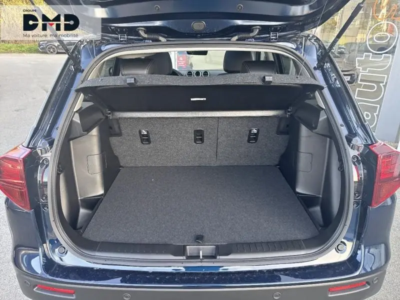 Coffre ouvert vu de l'arrière d'un Suzuki Vitara bleu So'Color Sphere avec banquette arrière rabattable et hayon relevé.