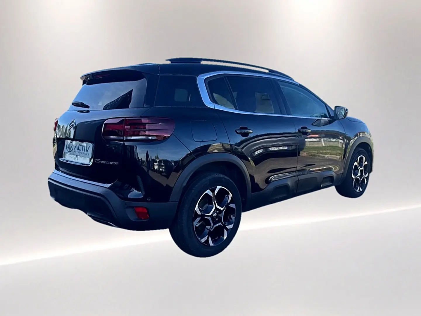 Citroën C5 Aircross noir vue 3/4 arrière droit avec barres de toit et jantes alu distinctives.