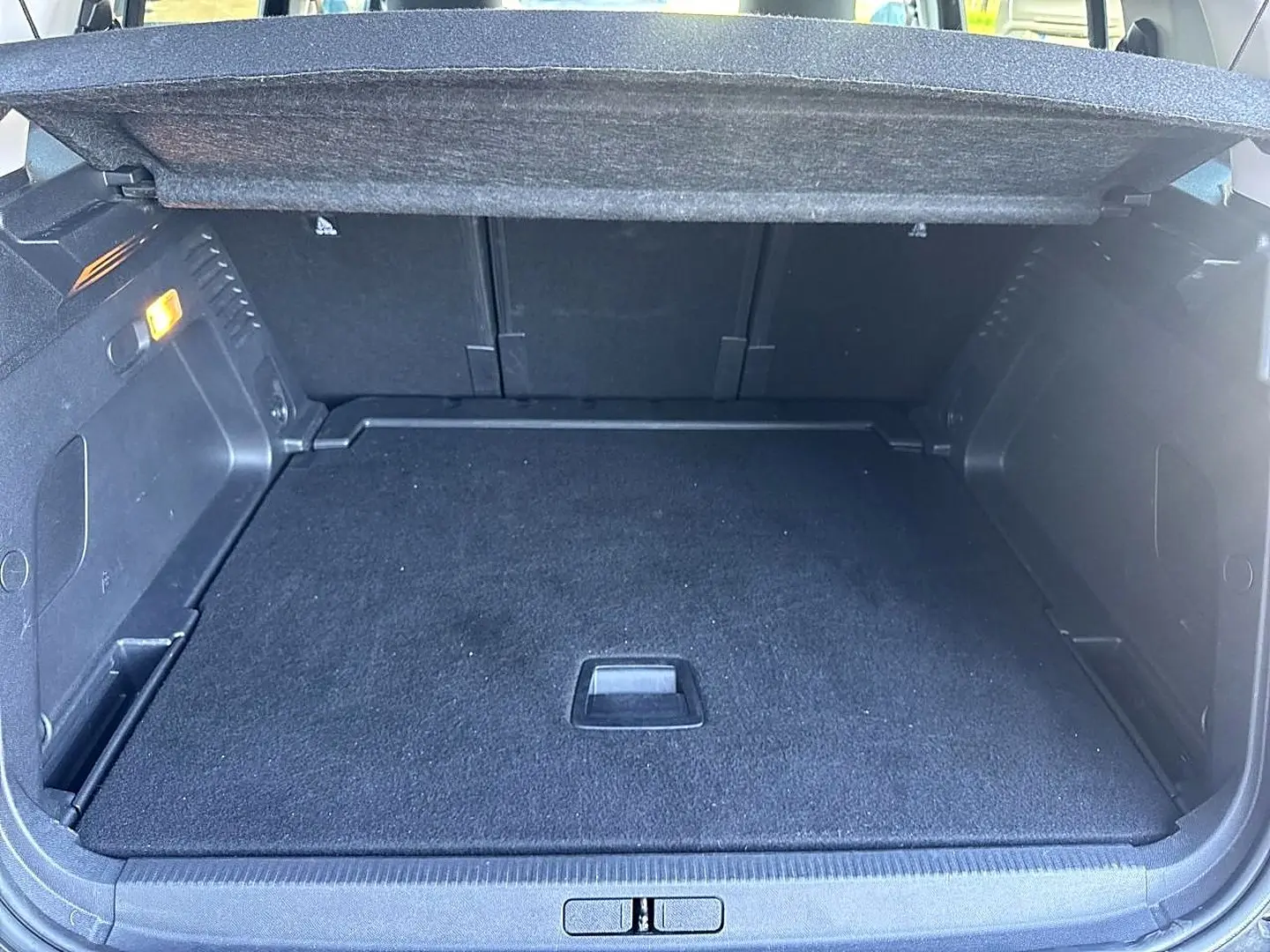 Coffre ouvert noir du Citroën C5 Aircross 1.2 hybride 145, vue arrière montrant le plancher plat et l'éclairage intérieur.