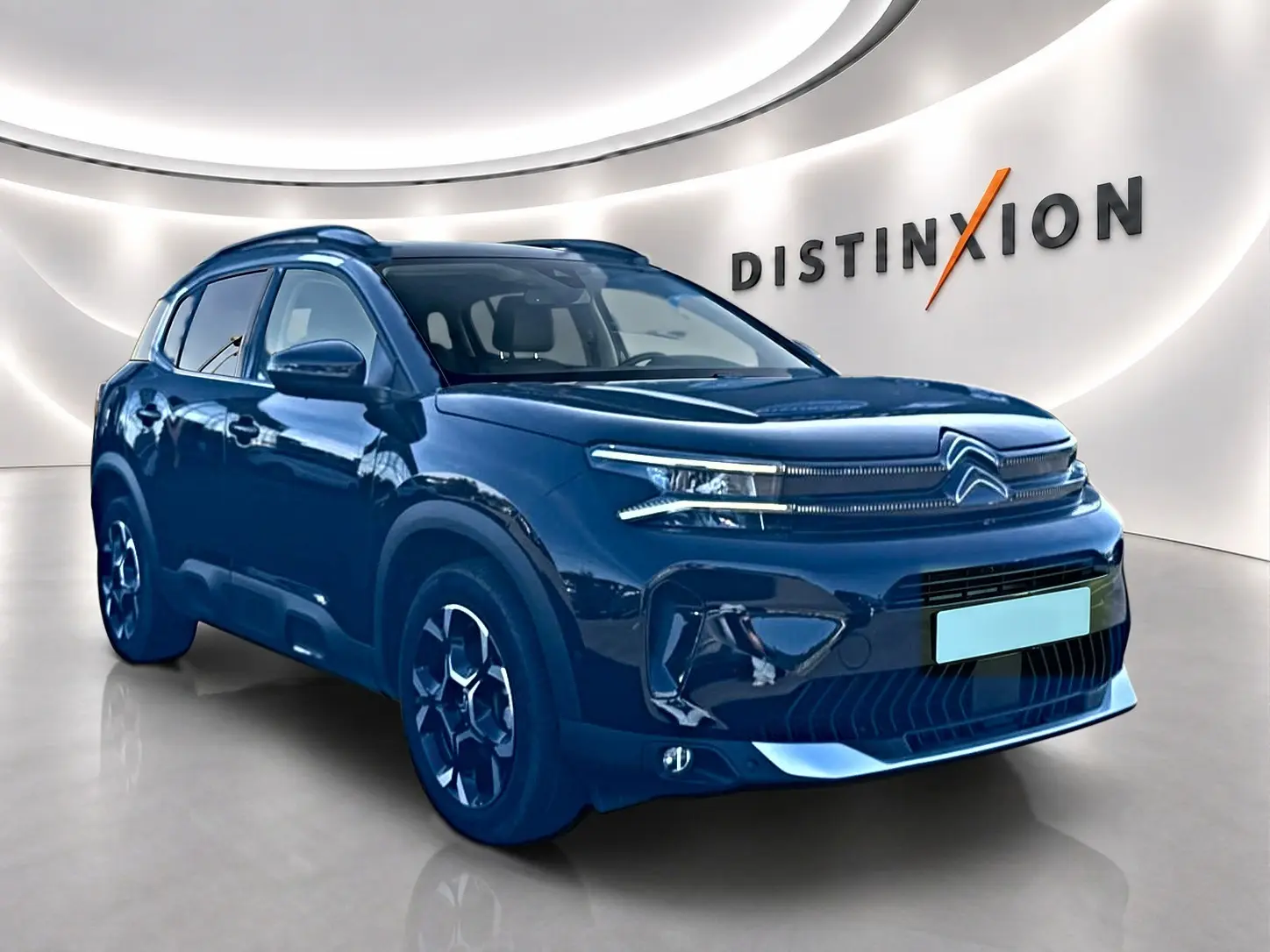 Citroën C5 Aircross noir en 3/4 avant droit dans un showroom avec jantes alu et barres de toit visibles.