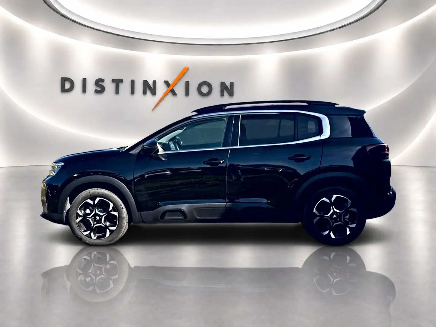 Profil côté gauche du Citroën C5 Aircross noir 2025 avec jantes alu et barres de toit visibles en showroom.