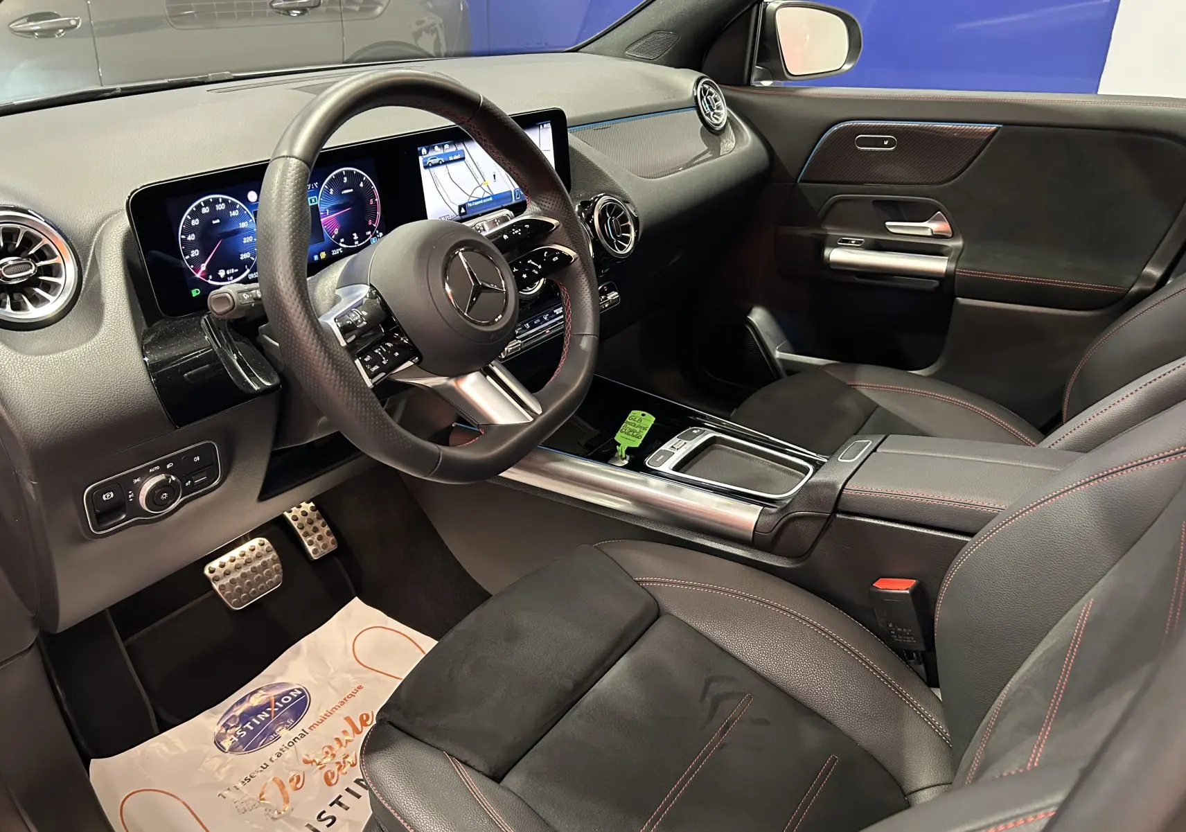 Intérieur côté conducteur du Mercedes GLA 200 D AMG Line 2024, avec tableau de bord numérique et sellerie cuir noir à surpiqûres rouges.