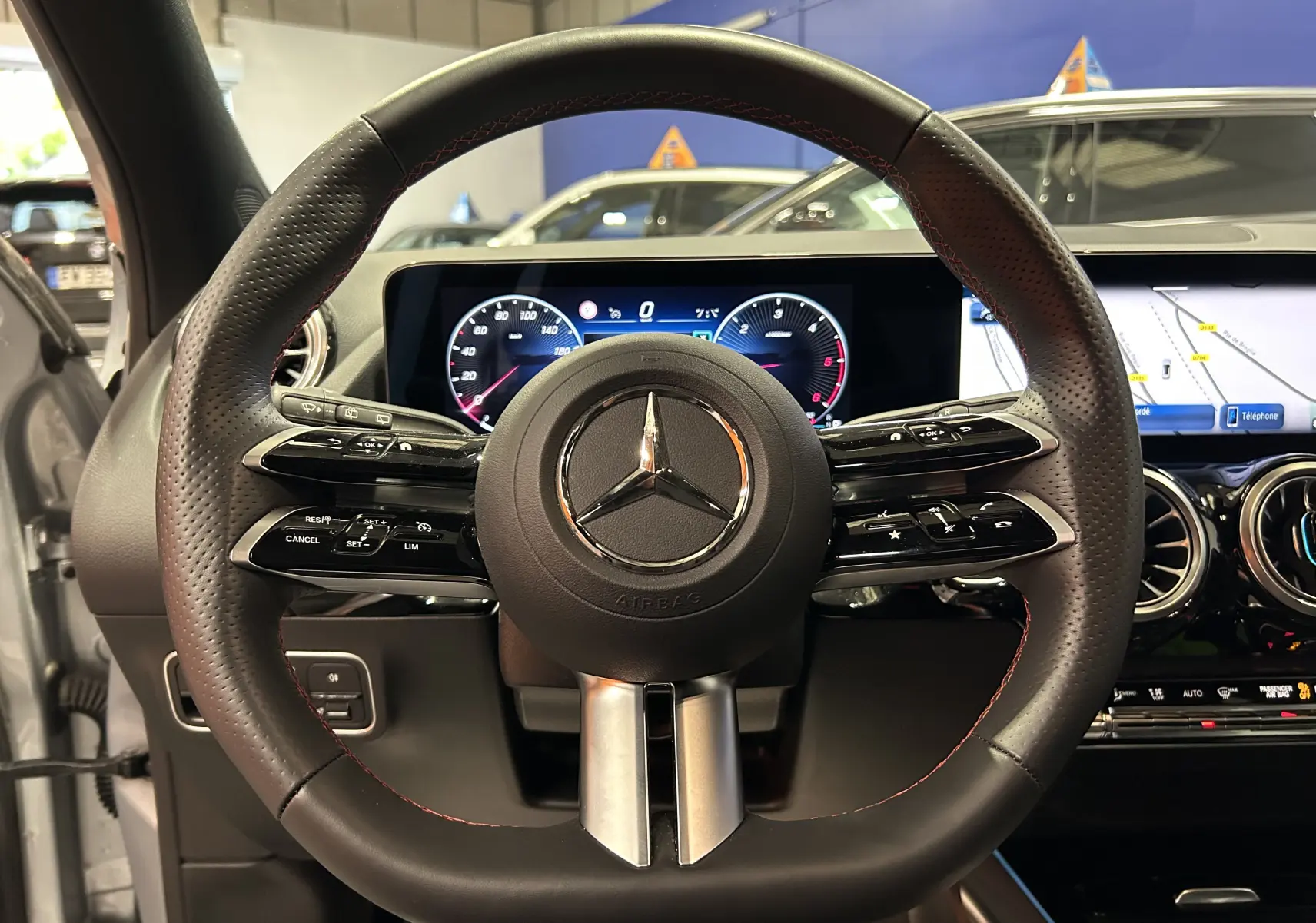 Volant en cuir perforé avec surpiqûres rouges du Mercedes GLA 200 D AMG Line 2024, tableau de bord numérique et écran tactile visibles.