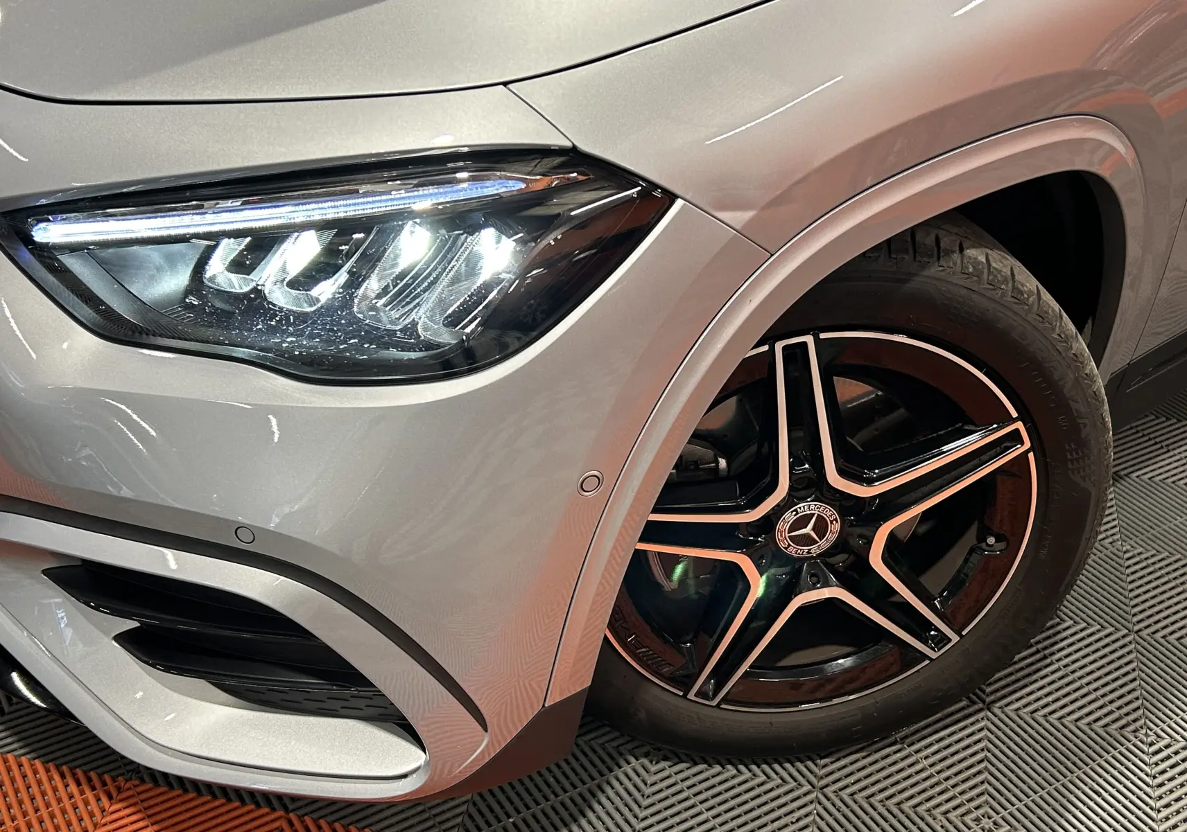 Gros plan sur l'avant droit d'un Mercedes GLA 200 D AMG Line 2024 argent High-tech avec jante AMG noire à 5 branches.