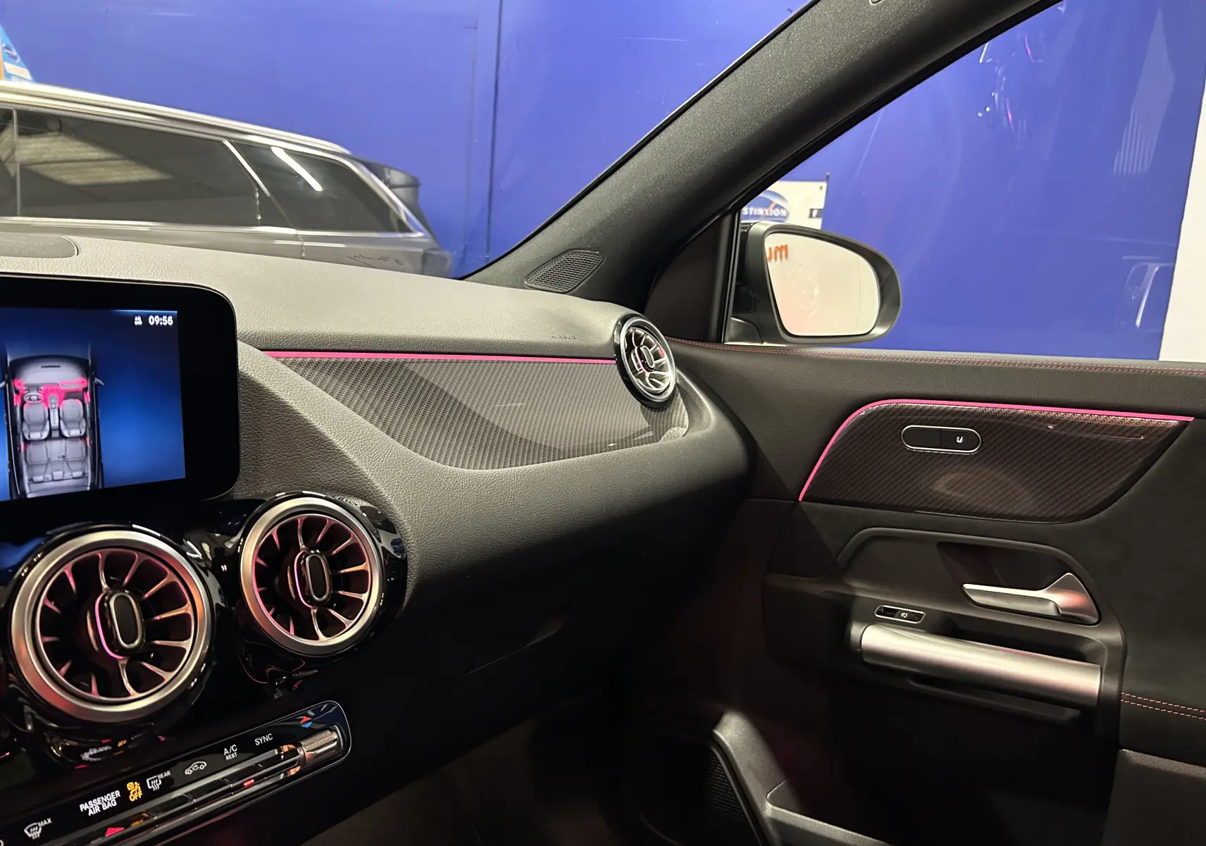 Intérieur côté passager du Mercedes GLA 200 D AMG Line 2024 avec éclairage d'ambiance rose et inserts carbone.