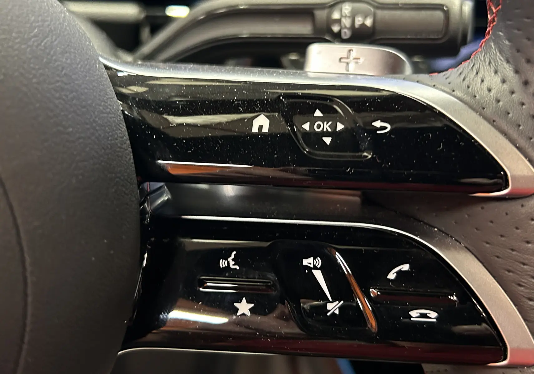 Gros plan sur les commandes multifonctions du volant cuir perforé d'une Mercedes GLA 200 D AMG Line 2024.