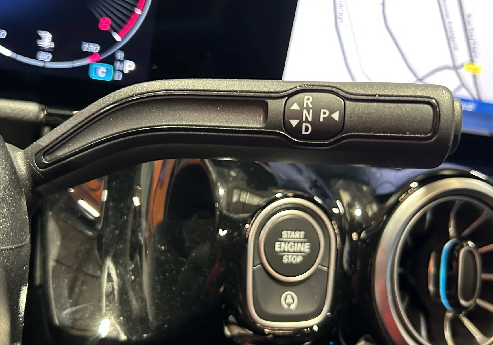 Gros plan sur la commande de boîte automatique et bouton start/stop du tableau de bord noir brillant d'une Mercedes GLA 200 D AMG Line 2024.