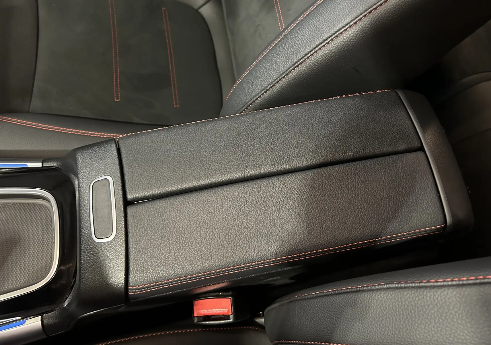 Gros plan sur l'accoudoir central en cuir noir avec surpiqûres rouges dans le Mercedes GLA 200 D AMG Line 2024.