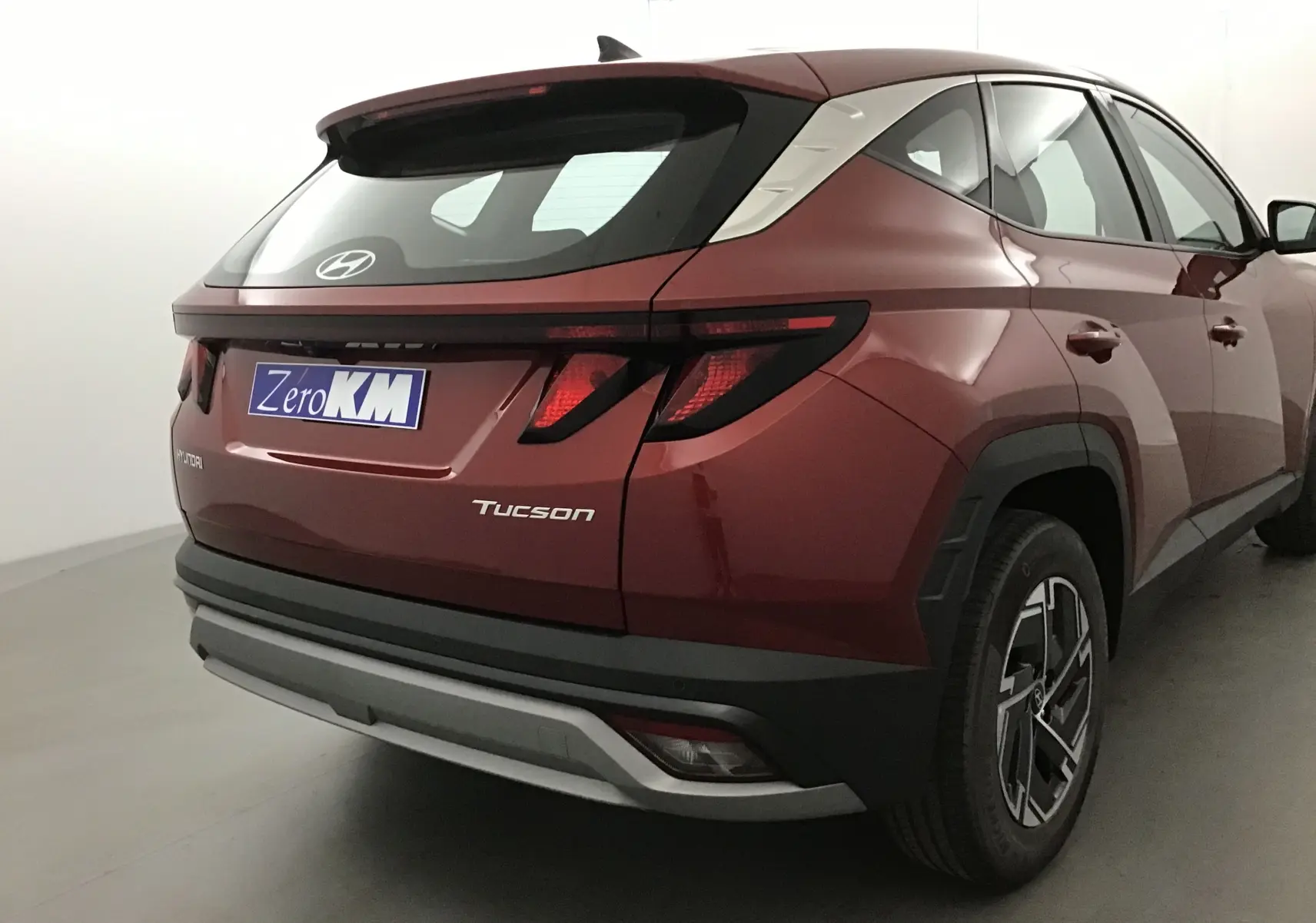 Vue 3/4 arrière droite du Hyundai Tucson rouge Ultimate 2025 avec feux arrière LED et jantes alliage noires.