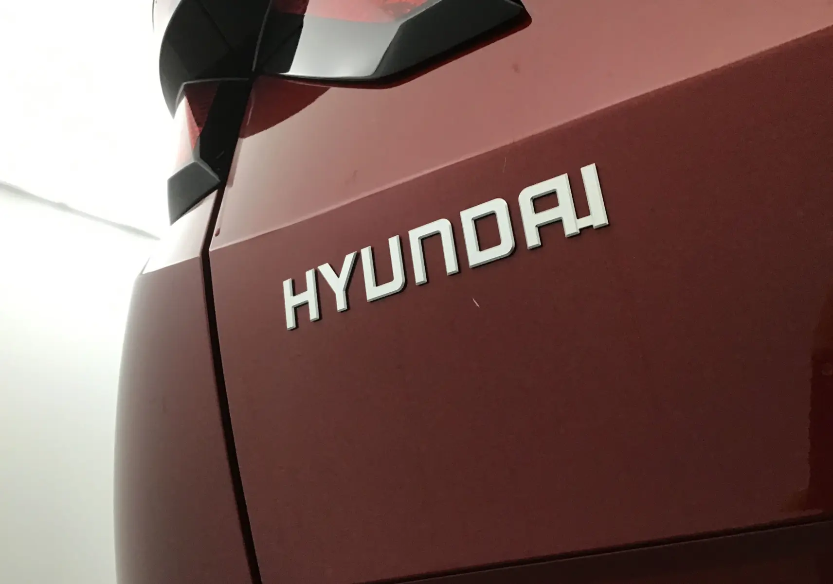 Gros plan sur l'arrière rouge Ultimate d'un Hyundai Tucson 2025, mettant en valeur le logo Hyundai et le feu arrière.