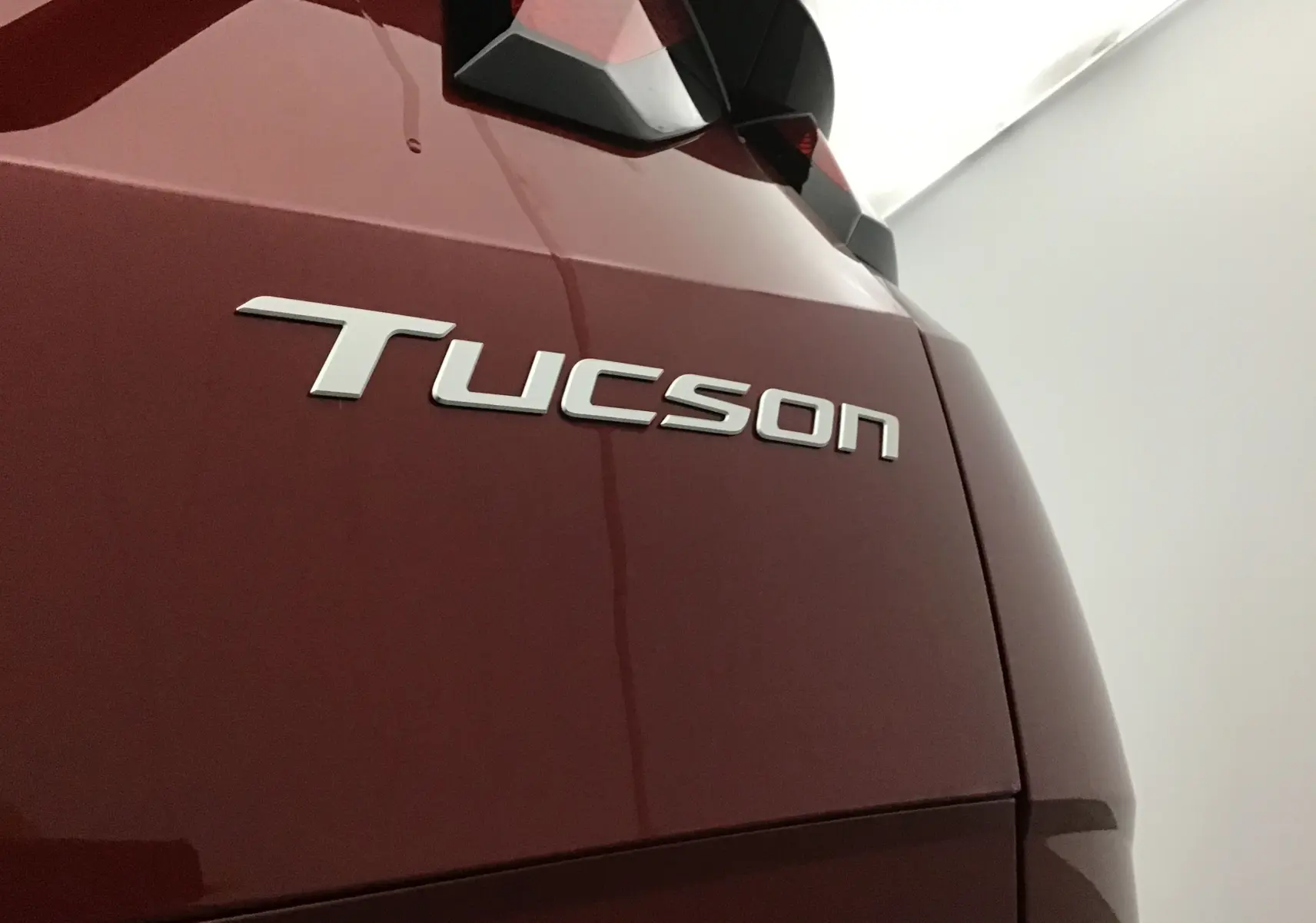 Gros plan sur l'arrière droit rouge Ultimate du Hyundai Tucson 2025 avec logo distinctif Tucson visible.