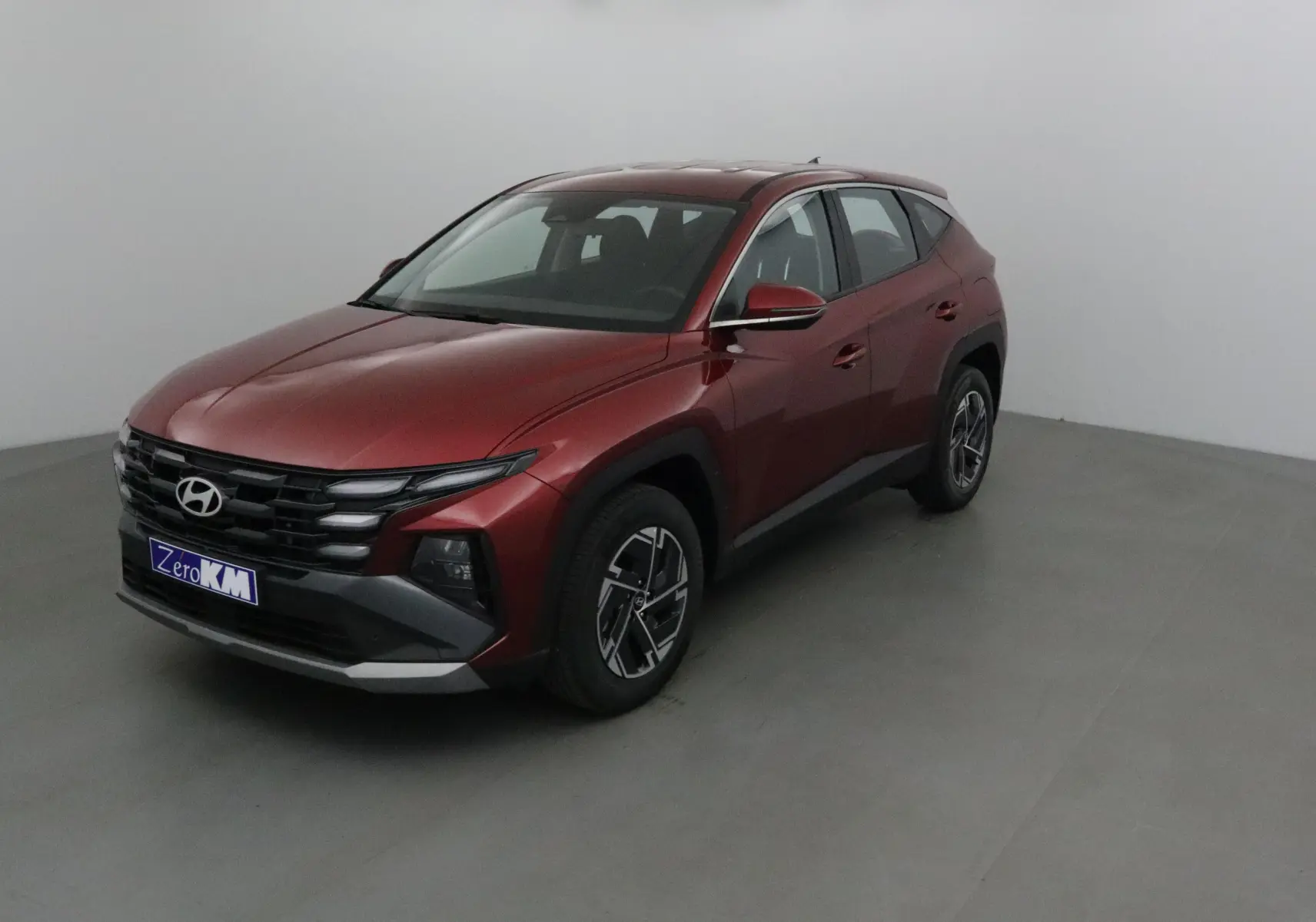 Hyundai Tucson 2025 rouge Ultimate en 3/4 avant droit, avec calandre noire et jantes alliage distinctives.