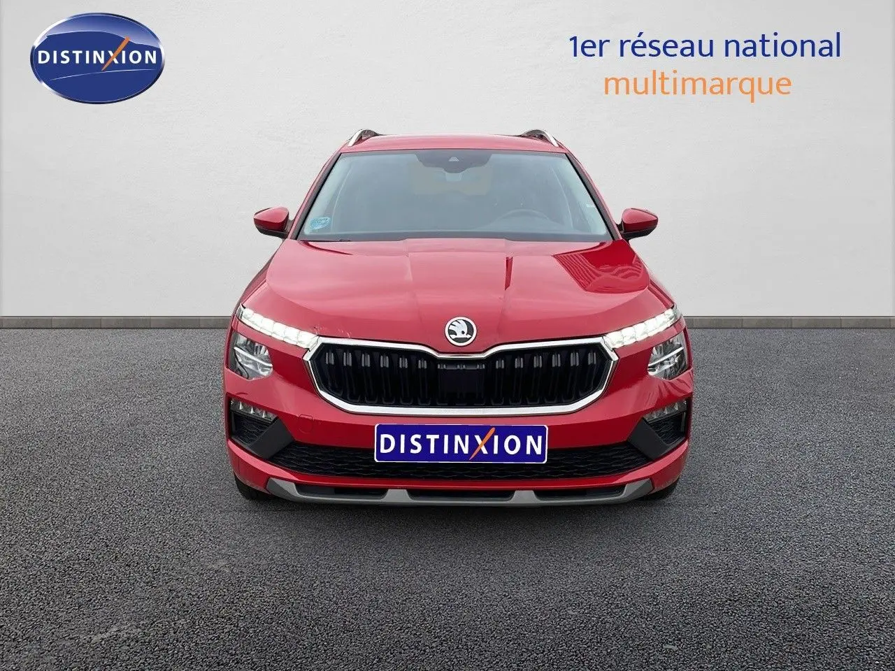 Vue frontale d'un Skoda Kamiq rouge Velvet Metal avec calandre noire et feux LED allumés sur fond neutre.