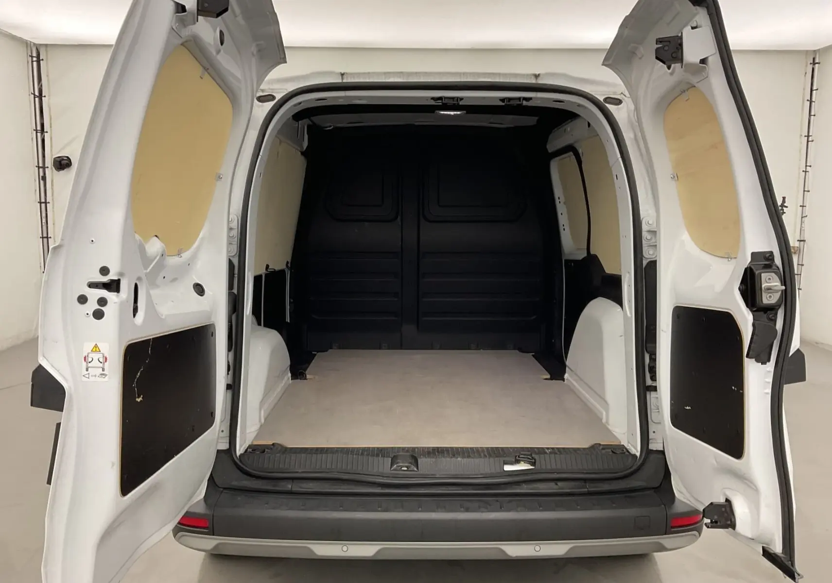 Vue arrière du Renault Kangoo Van blanc 2024 avec portes arrière ouvertes et espace de chargement vide et protégé.