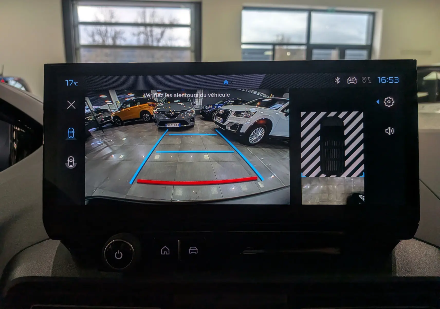 Vue de l'écran intérieur montrant la caméra de recul du Peugeot Rifter noir avec guidage de trajectoire en bleu et rouge.