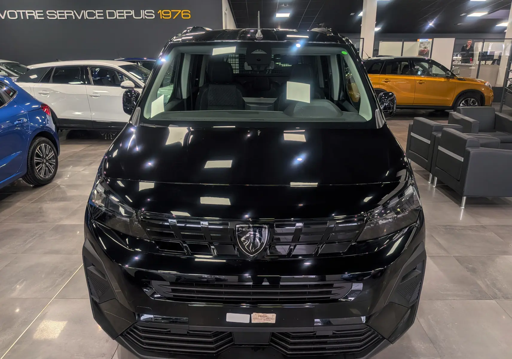 Peugeot Rifter noir vue 3/4 avant droit en showroom, avec calandre et optiques modernes visibles.