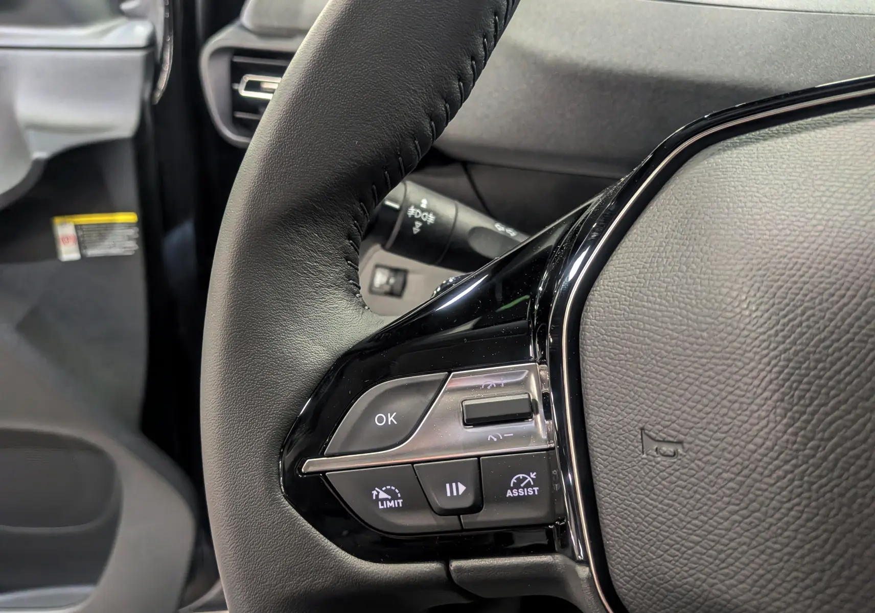 Gros plan sur le volant noir du Peugeot Rifter 2025, avec commandes intégrées et détails en plastique brillant.